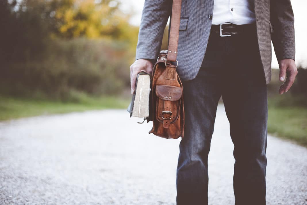 Canva - Man Holding Book Standing on the Road